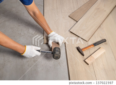 Worker Installing Interlocking laminate floor, home renovation. Worker Installing Interlocking laminate floor, home renovation. 137022397