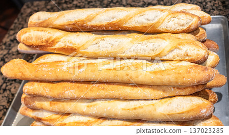 Stack of crispy baguettes coming out of the oven at the bakery. French bread 137023285