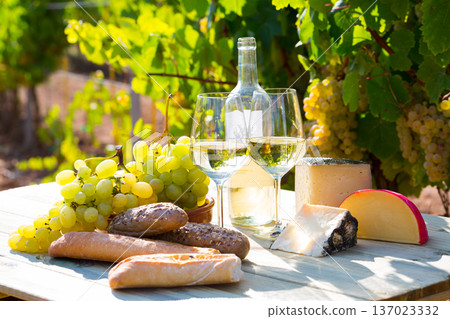 White wine with cheese, bread and grapes in vineyard 137023332