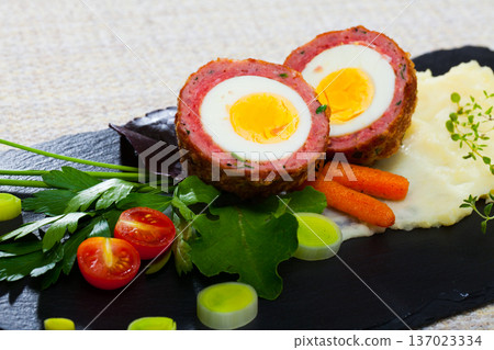 Dishes of traditional Scottish cuisine of scotch egg served with greens and potatoes 137023334