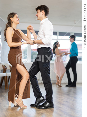 Elegant couple performs an expressive latin american dancing in bright, modern dance studio during group class 137023373