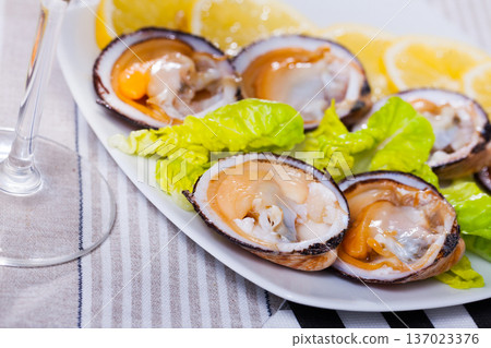 Tasty raw dog cockle, lemon and greens at plate and glass of wine 137023376