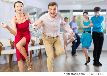 Dynamic pair engaging in Latino dance in dance studio. Pairs training ballroom dance in studio Dynamic pair engaging in Latino dance in dance studio. Pairs training ballroom dance in studio 137023436