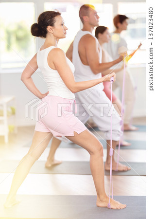 Young woman doing shoulder workout with resistance band in standing positions 137023480