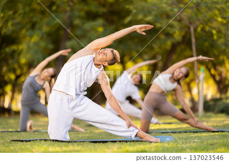 Man performing stretching exercises at outdoor yoga session Man performing stretching exercises at outdoor yoga session 137023546