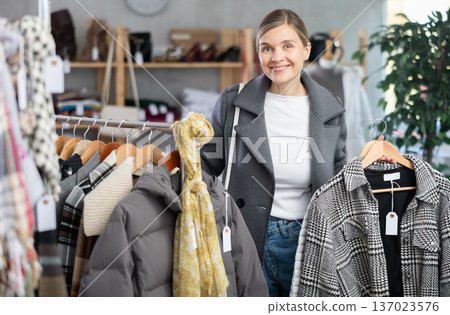Adult woman chooses coat in clothing store Adult woman chooses coat in clothing store 137023576