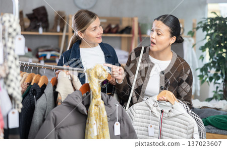 Two women friends browsing goods items and choose elect something autumn outwear 137023607