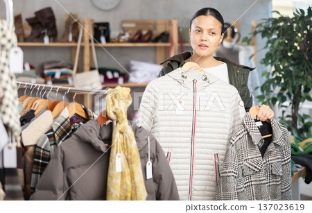Asian woman browsing goods items and choose elect plaid jacket coat or down jacket 137023619