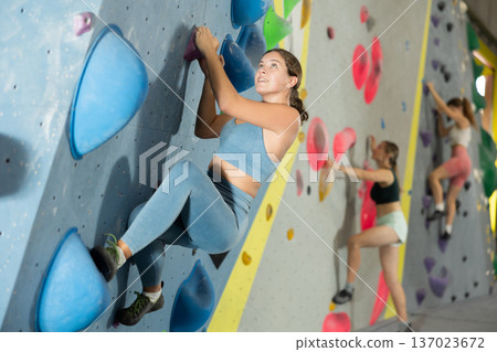 Woman exercising on wall in climbing gym during bouldering training 137023672