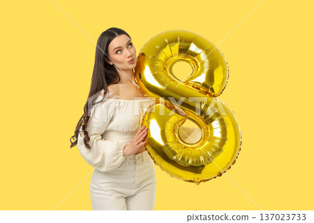 Young woman celebrates day holding golden balloon shaped like 8 137023733