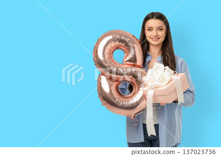 Young woman holds a gift box and balloon for celebration Young woman holds a gift box and balloon for celebration 137023736