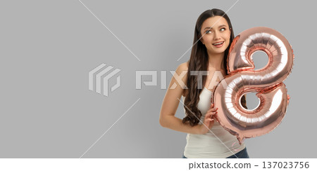 A woman smiles with a shiny balloon shaped like 8 A woman smiles with a shiny balloon shaped like 8 137023756