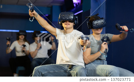 Young couple with VR goggles and controllers playing in virtual reality room 137023771