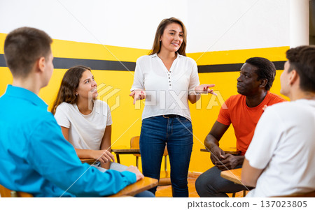 Portrait of delighted girl student with her groupmates and female teacher in auditorium Portrait of delighted girl student with her groupmates and female teacher in auditorium 137023805