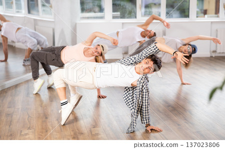 Man and his students perform hip hop dance on one bent leg, movement in horizontal plane near floor Man and his students perform hip hop dance on one bent leg, movement in horizontal plane near floor 137023806
