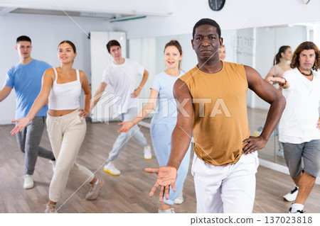 Cheerful multiracial people stretching out hand during dancing training in studio 137023818