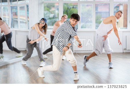 Young man standing performs basic hip hop movements in front of group of students Young man standing performs basic hip hop movements in front of group of students 137023825
