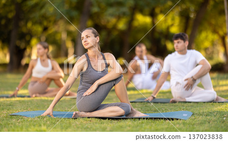 Woman performing twisting asana Matsyendrasana in summer park Woman performing twisting asana Matsyendrasana in summer park 137023838