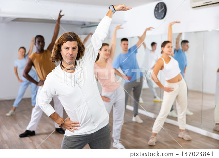 Group of happy young adult multinational sports people exercising dancing in modern gym studio Group of happy young adult multinational sports people exercising dancing in modern gym studio 137023841