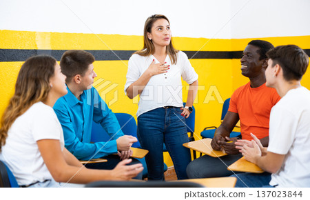 Female student discussing with groupmates sitting in circle in auditorium during classes 137023844
