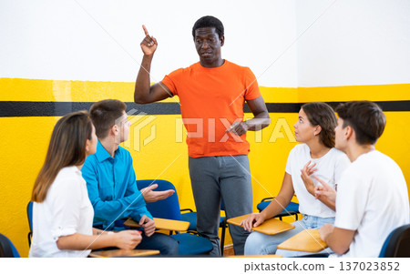 Student group lively discussing while sitting in circle in auditorium 137023852