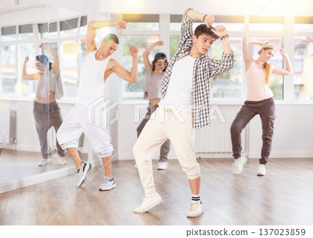 Young guy practicing basic hip hop moves in training hall 137023859