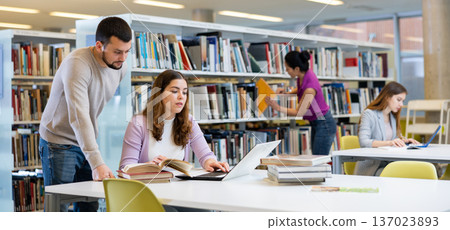 Man recommending books to woman in public library 137023893