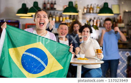 Emotional friends, football fans cheering for favorite Brazil team together while watching match on tv in bar 137023949