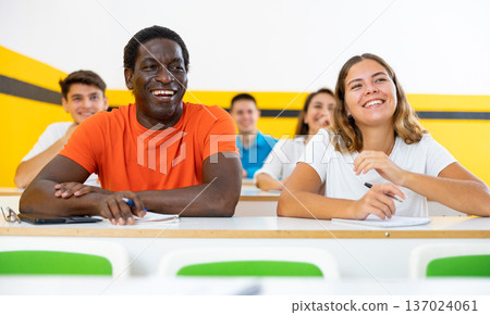 Cheerful smiling adult students at their desks in university classroom Cheerful smiling adult students at their desks in university classroom 137024061