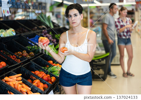 Woman selecting tomatoes in grocery store Woman selecting tomatoes in grocery store 137024133