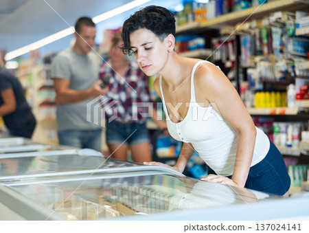 Woman is choosing frozen food for dinner in supermarket 137024141