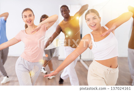 Joyful flexible multiethnic men and women exercising active moves with group of people in dance center Joyful flexible multiethnic men and women exercising active moves with group of people in dance center 137024161