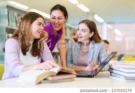 Three female friends studying together at library Three female friends studying together at library 137024174
