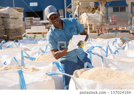 African american worker keeps records of bulk construction materials in warehouse African american worker keeps records of bulk construction materials in warehouse 137024184