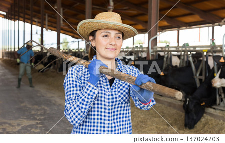 Successful young female cow breeder standing in cowshed Successful young female cow breeder standing in cowshed 137024203