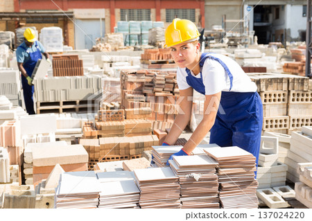Female worker carrying ceramic tiles at warehouse 137024220