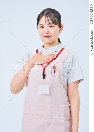 A woman in a white coat with her hand on her chest A woman in a white coat with her hand on her chest 137024289