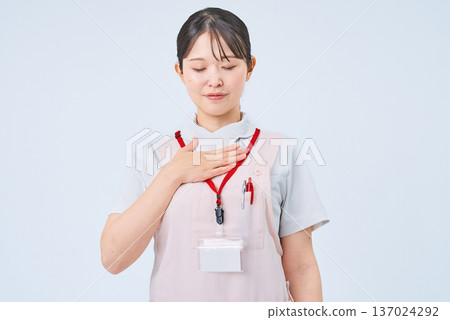 A woman in a white coat with her hand on her chest 137024292