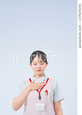 A woman in a white coat with her hand on her chest 137024293