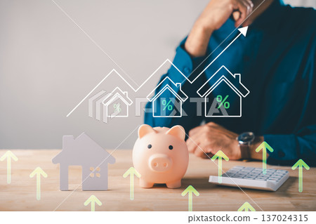 Real estate investment piggy bank saving money for home house property shows house icons growth graph while man calculates insurance budget with rising mortgage interest rates Real estate investment piggy bank saving money for home house property shows house icons growth graph while man calculates insurance budget with rising mortgage interest rates 137024315