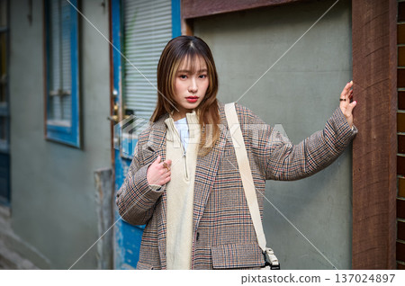 一位身穿格子外套的日本女子站在街角。秋冬時尚人像,20-30歲,戶外。 一位身穿格子外套的日本女子站在街角。秋冬時尚人像,20-30歲,戶外。 137024897