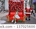 Woman sitting on red Santa sofa with ornament wall Christmas backdrop 137025600