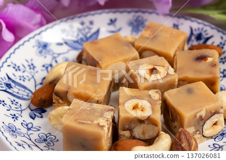 Butter fudge squares with nuts in a saucer with pink wisteria. Butter fudge squares with nuts in a saucer with pink wisteria. 137026081