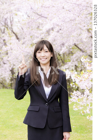 An office lady raising her index finger in front of the cherry blossoms 137026328