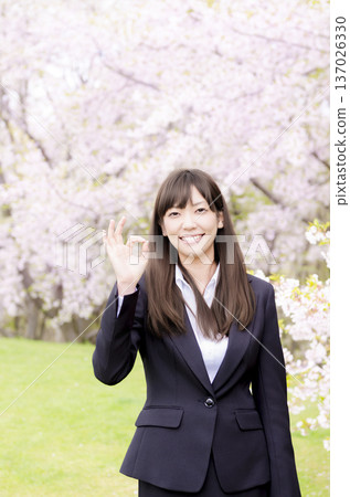 An office lady giving an OK sign in front of cherry blossoms 137026330
