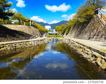 Autumn city river and promenade with mountain and building views Autumn city river and promenade with mountain and building views 137026736