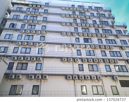Densely packed windows on the building wall and many outdoor units 137026737