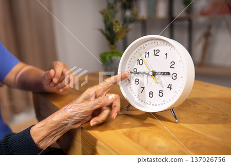 Asian Elderly Woman with Dementia Practicing Read Time on Clock. Asian Elderly Woman with Dementia Practicing Read Time on Clock. 137026756