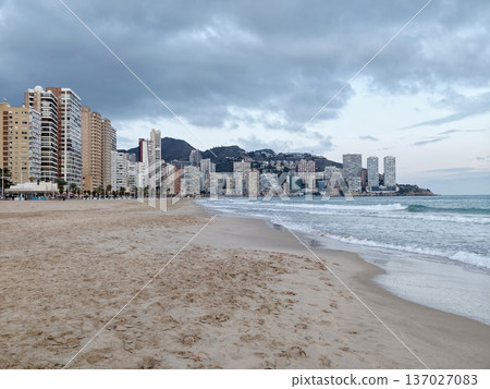 Peaceful coastal scene, Peaceful early morning by beach featuring lone person and hazy city backdrop 137027083