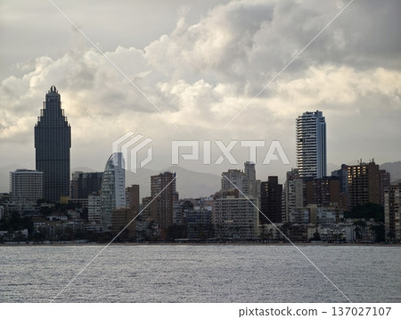Stormy cityscape evening, Dramatic urban horizon under heavy clouds with ships and industrial cranes Stormy cityscape evening, Dramatic urban horizon under heavy clouds with ships and industrial cranes 137027107
